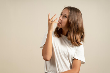 Portrait of a Latin teenage girl sucking her fingers after having eaten something delicious,...