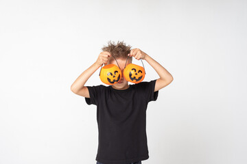 Kids Halloween. A beautiful emotional boy in a black T-shirt holds Jack's lanterns on a white studio background.