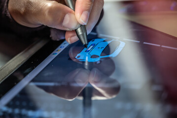main en train de dessiner avec un stylet sur une tablette numérique
