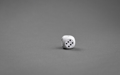 A white dice lies on a gray background selective focus copy space