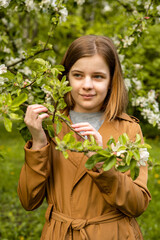 Young teenage girl with an apple tree branch in a flowering garden in the spring. Portrait. High quality photo