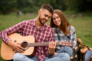 close-up of beautiful young man and woman relaxing in nature with guitar