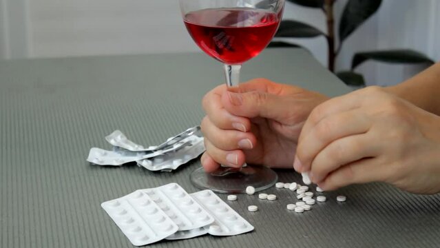 A woman sprinkles pills with her fingers, making a decision to commit suicide. Pills on female hands. The concept of suicide or mental disorder.