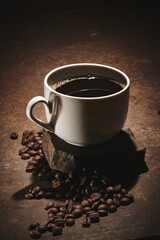 Cup of freshly brewed roasted coffee beans on brown background