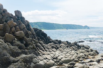 gray basalt rocks against a blurred coastal seascape