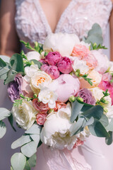 a beautiful wedding bouquet of various flowers and greenery in the hands of the bride.
