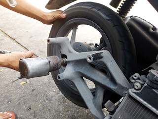 Close up of a motorcycle mechanic using an air gun to loosen the wheel nuts in a mechanical workshop