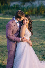 Fototapeta premium An unusual, picturesque walk of a newlywed couple on their wedding day. A young man in a suit and a beautiful, slender bride in a wedding dress.