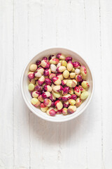 Colorful beans in a white bowl on a white wooden background. Bright purple white beans. Top view. Copy space.