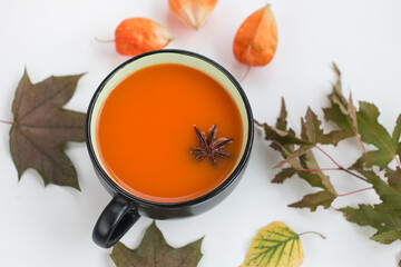 Pumpkin soup with cream and pumpkin seeds and a bucket on a white wooden background. Copy space.