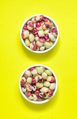 White purple beans in two bowls on a yellow background. Top view.