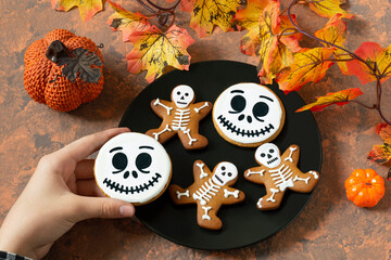 Hand of girl put Halloween gingerbread on plate