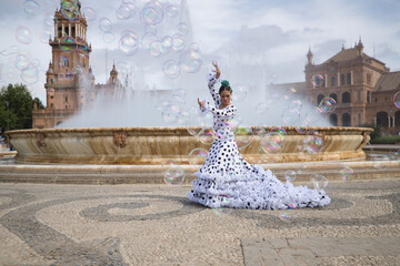 Young teenage woman in white suit with black polka dots, dancing flamenco in front of water...