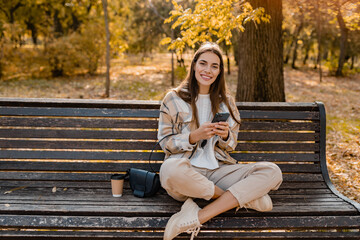 Obraz premium attractive young woman walking in autumn wearing jacket using phone