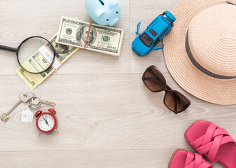 Fototapeta na wymiar A piggy bank with dollar bills in a travel setting. In the composition of the image: Sun Hat, Alarm Clock. Concept of saving money for traveling on vacation.