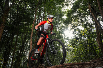 Mountain bikers ride MTB, mountain bike downhill to the extreme. Asian man rides MTB, mountain bike...