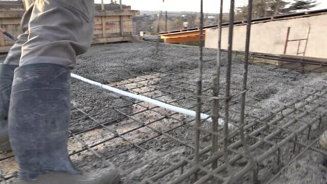 Concreting of reinforced concrete slab. Worker concretes foundation, rebar, pour cement mortar on reinforcing mesh or cage from pump concrete mixer. Builders are building a factory, hangar, house