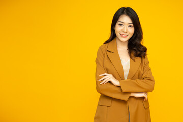 Young Asian business woman smiling with arms crossed isolated on yellow background