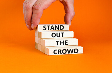 Stand out the crowd symbol. Concept words Stand out the crowd on wooden blocks on beautiful orange...