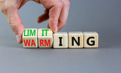 Limiting global warming symbol. Concept words Limiting and Warming on wooden cubes. Businessman hand. Beautiful grey table grey background. Business limiting global warming concept. Copy space.