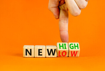 New low or high symbol. Concept words New high and New low on wooden cubes. Businessman hand. Beautiful orange table orange background. Business new low or high concept. Copy space.