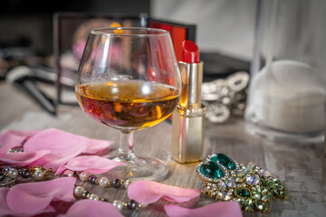 petit verre de bourbon sur une table de loge avec du maquillage et des bijoux