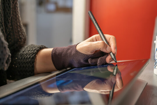 main en train de dessiner sur une tablette tactile avec un stylet