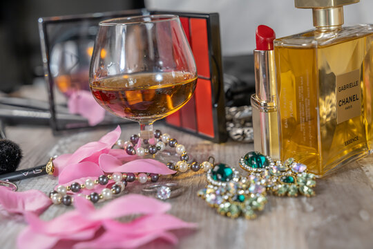 Maquillage et bijoux dans une loge avec un verre ballon rempli d'alcool