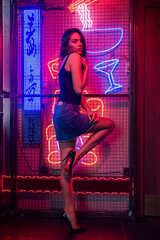 Young beautiful brunette woman in motion. Red blue color mixed light. Attractive girl in a shiny evening dress is dancing in night club. Hair flutters fly. Black background long exposure. Disco effect