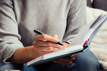 Online working, remote learning at home. Woman hands taking notes in open notebook during online...