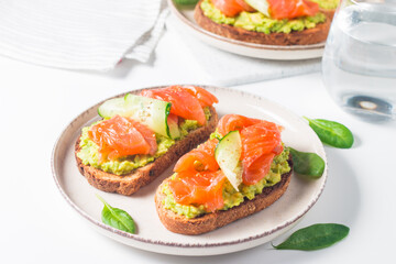 Open sandwich with smoked and salted salmon for healthy breakfast. Trout and avocado on bruschetta toast. 