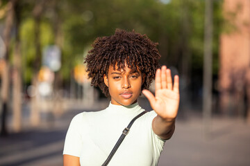 Young woman making a stop or stop gesture with the raised palm of her hand as she blocks access or puts an end to something - obrazy, fototapety, plakaty