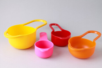 Colorful plastic measuring spoons and measuring cups on bright background