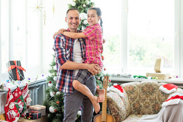 Happy father and his little daughter decorating the Christmas tree at home.