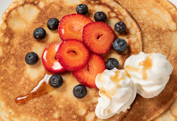 Pancakes with strawberries, blueberries, cream and syrup