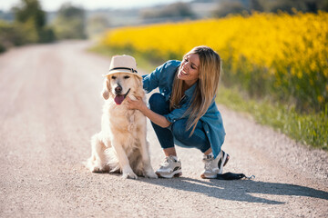Attractive young woman caring and playing with her beautiful golden retriever dog in a rapessed...