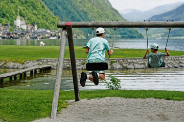 Two brothers ride on a swing at Hallstatt, Austria.