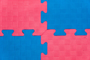 Eva foam rubber floor puzzle mats texture, colorful floor mat background. Multicolored soft elements. Blue and pink puzzles connected