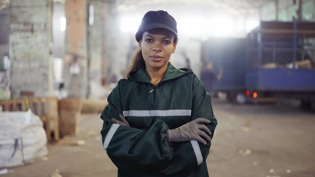 portrait of an African-American woman in a special green uniform against the background of the interior of a waste processing plant. Processing of raw materials, recycling. Pollution control