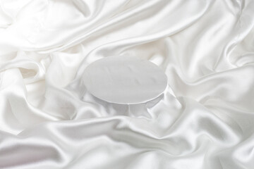 Silver white satin fabric with shiny folds and a round stage in the middle