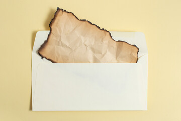 Ancient parchment with burned margins in a opened envelope