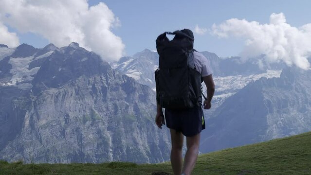 Man with backpack trekking in Swiss alps, Grindelwald Jungfrau Region. 4k video 29.97 fps(Panasonic S1 Vlog, Apple ProRes422HQ)