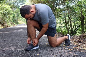 Normal weight man tying shoelace while looking at black shoe