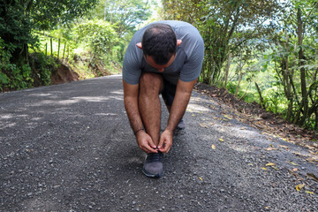 Normal weight man tying shoelace while looking at black shoe