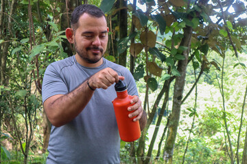Sporty young man opening an orange bottle with a black cap