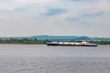 Fototapeta na wymiar A dry cargo ship floats along a wide steppe river