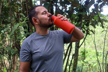 Sporty young man drinking from an orange bottle 