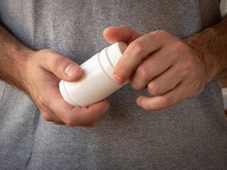 Men's hands open a plastic white jar with medicines or multivitamins. Treatment and prevention of diseases