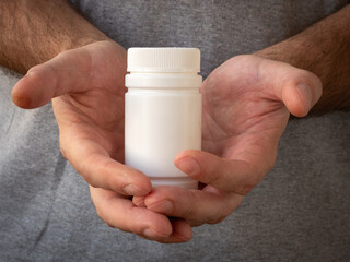 Plastic white jar with medicine pills in men's hands