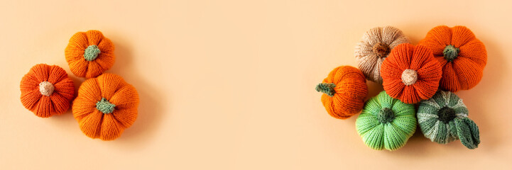 Knitted orange and green pumpkins on an orange background, autumn composition, banner. Halloween concept.